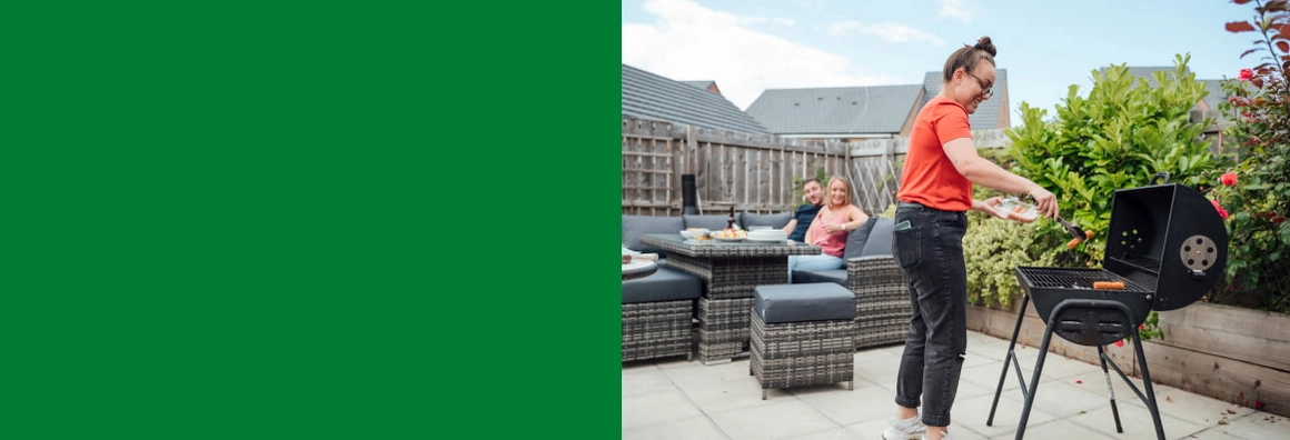 Eine Person legt mit einer Grillzange Grillgut auf den Grill.